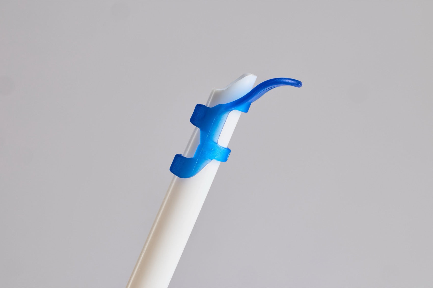 A LinguaGuard tongue retractor attached to the vented end of a white HVE suction straw
